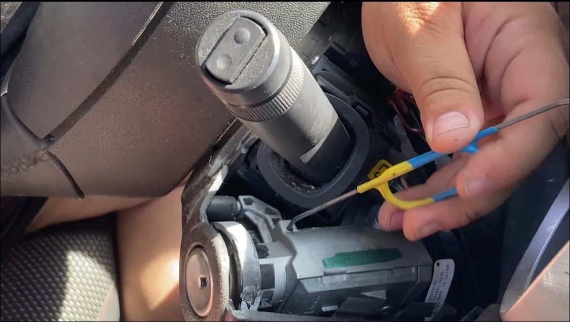 Auto locksmith repairing a car ignition barrel behind the steering column