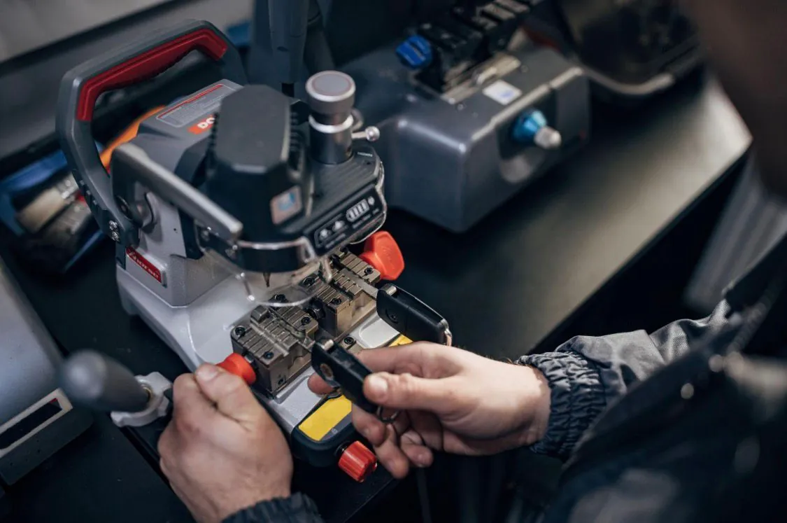 Locksmith cutting a car key blade on a precision key cutting machine