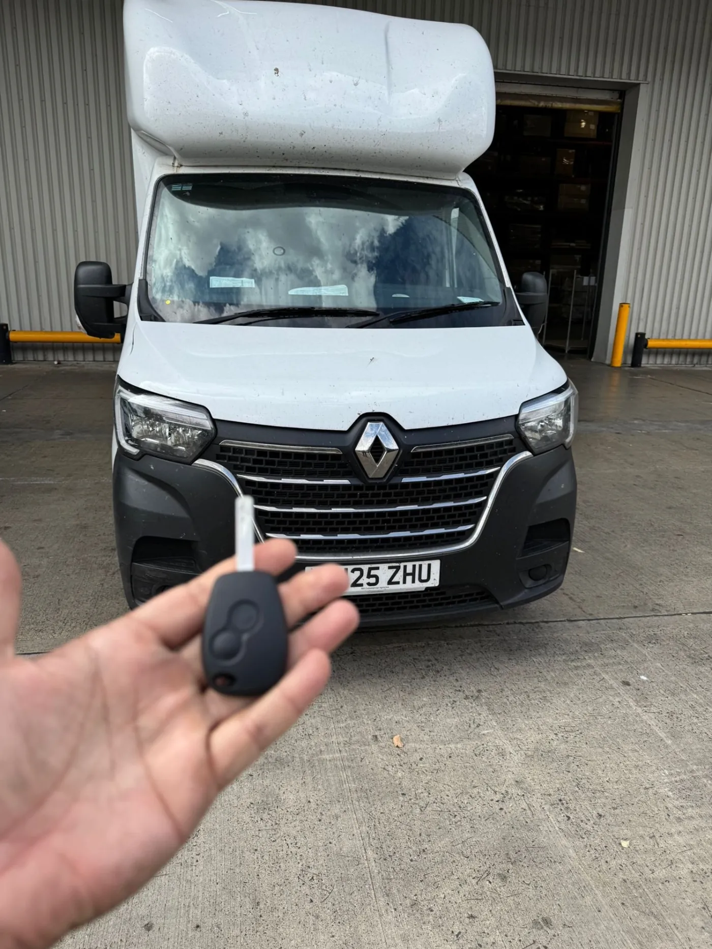 New replacement van key held in front of a white Renault Master luton van